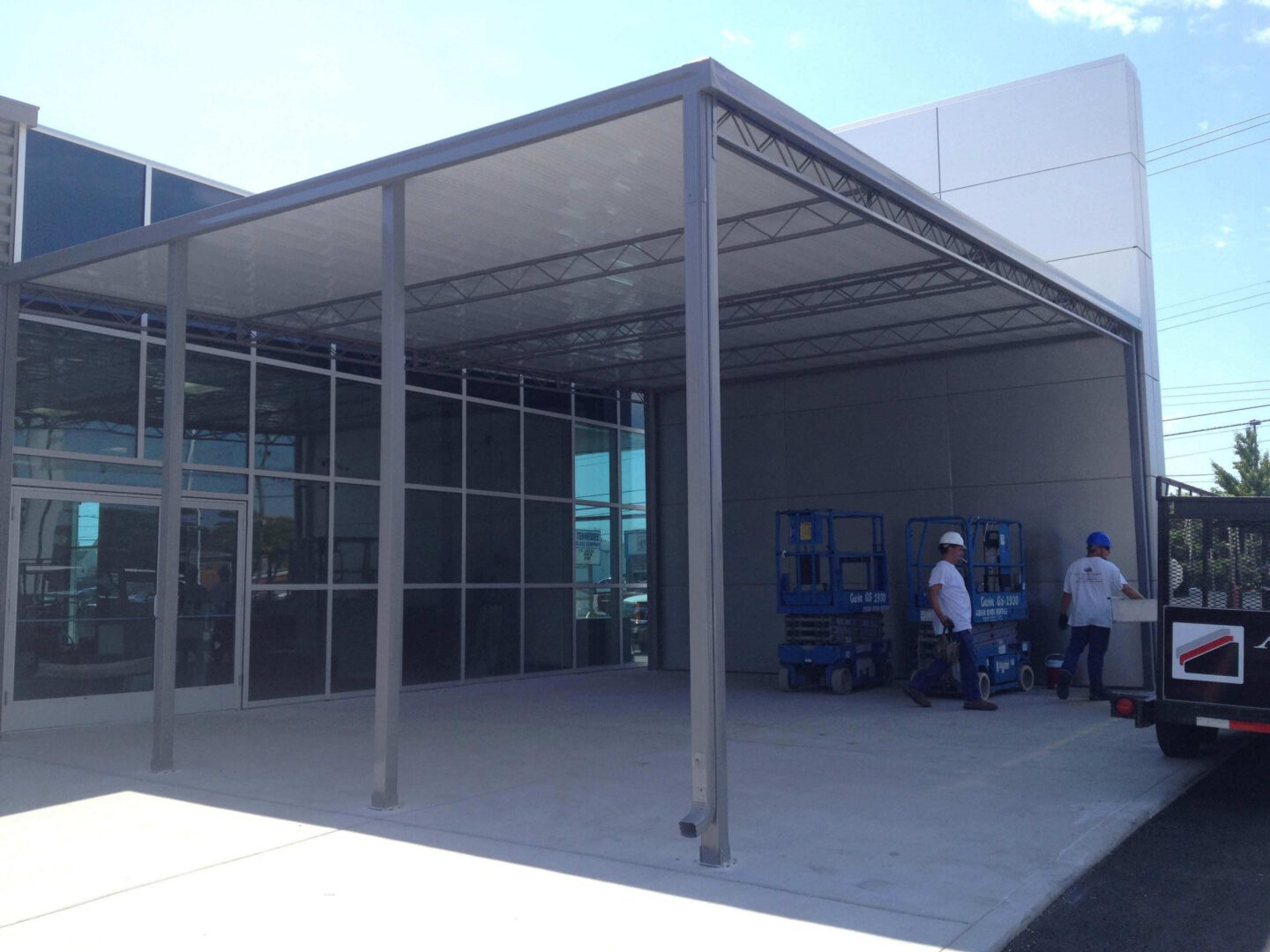 Car dealership metal entry canopy with workers